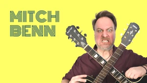 Mitch Benn with two guitars, making a funny face : Office-Watch.com