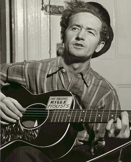 Woody Guthrie plays guitar with "This Machine Kills Fascists" sticker : Office-Watch.com